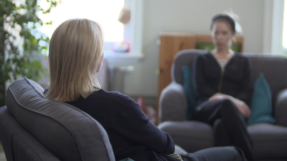 Woman sat with back to camera and other woman blurred out sat on sofa